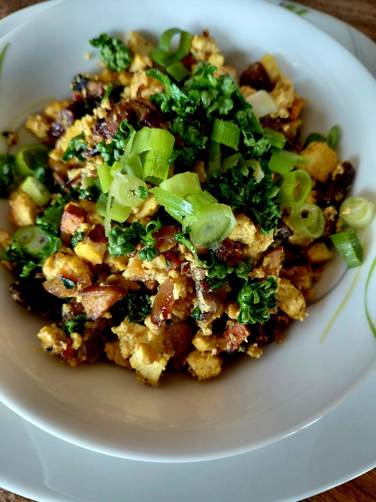 NaturTeller – vegane Ernährungsberatung - Eine helle, flache Schüssel mit einem cremigen Gemüsecurry, serviert mit Reis. Das Curry links enthält Blumenkohlröschen, in Scheiben geschnittene braune Champignons und Frühlingszwiebeln in einer gelblichen Soße. Rechts befindet sich ein Berg weißen Reis, ebenfalls mit gehackten Frühlingszwiebeln garniert.